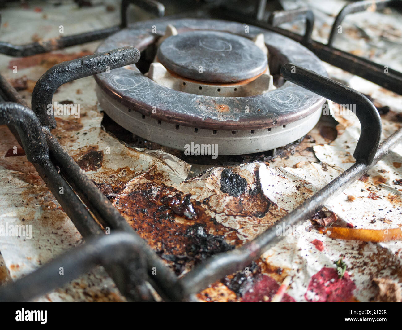 La sporco e sudicio e arrugginita top della cucina a gas di cottura con i  bit di stagnola sotto il metallo con pezzetti di cibo e di alta Detaul  splendente di crepe
