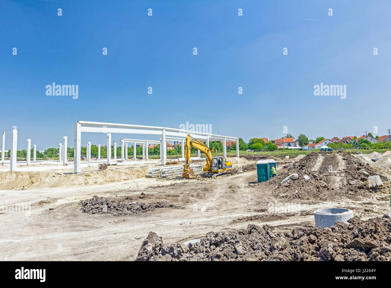 Concetto di architettura, lo scheletro di cemento di un nuovo edificio con mobile toilette in plastica. Foto Stock
