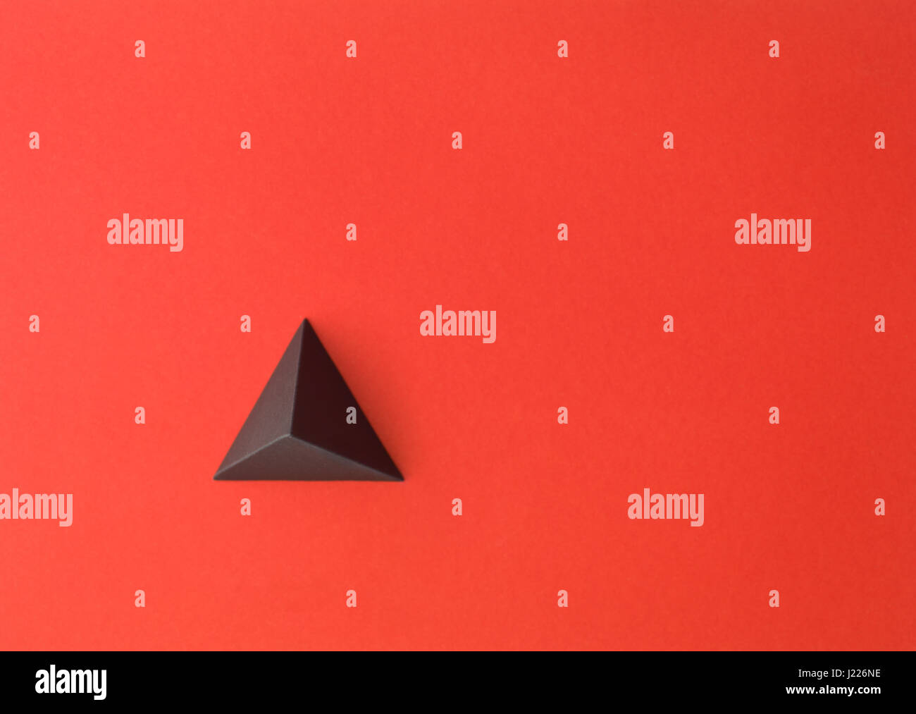 Carta rossa tetrahedron su carta rossa. Copia dello spazio disponibile. È utile per le carte aziendali e web Foto Stock