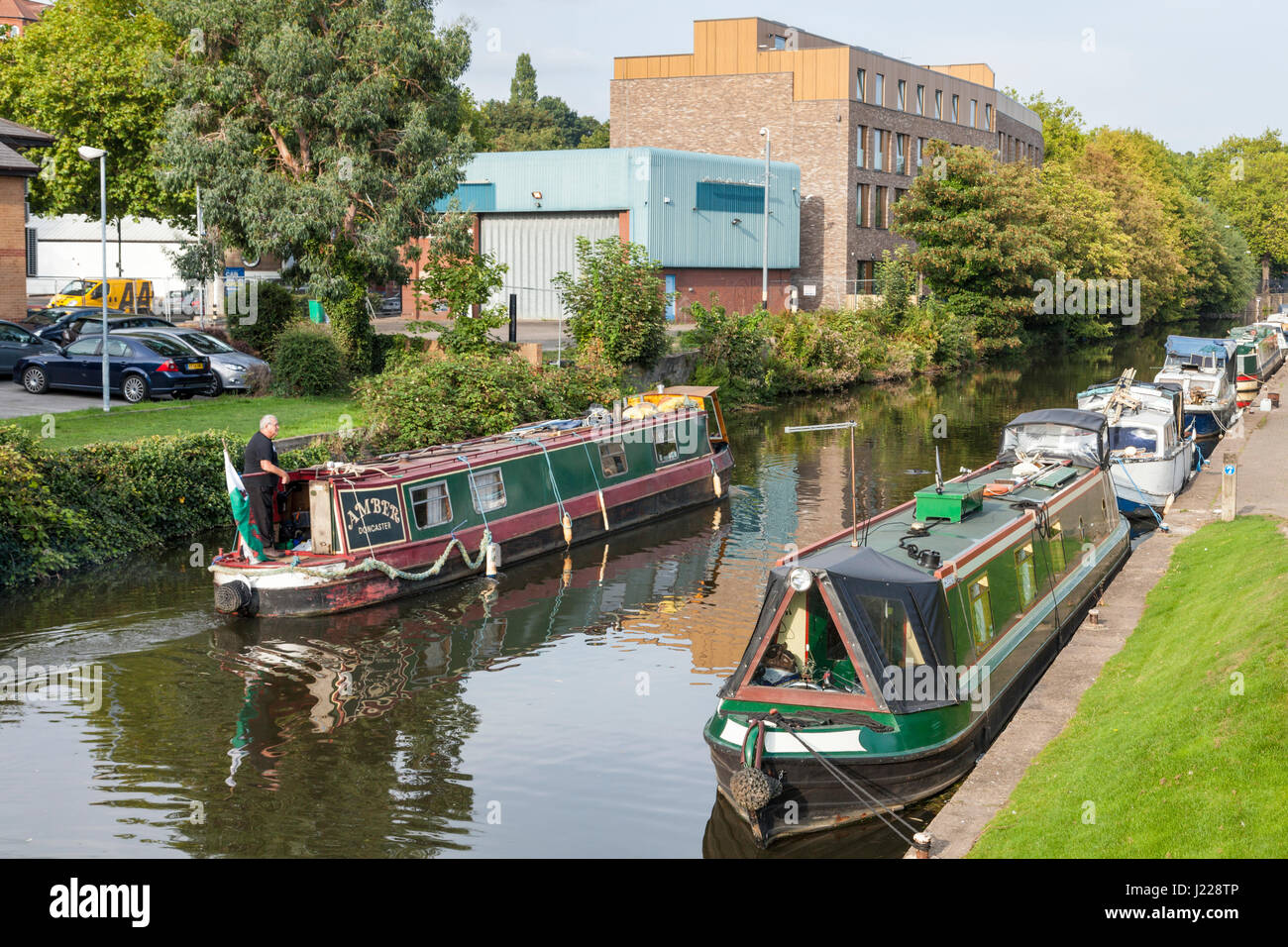 Narrowboat passando altre barche ormeggiate su un canale della città. Nottingham e Beeston Canal, Nottingham, Inghilterra, Regno Unito Foto Stock