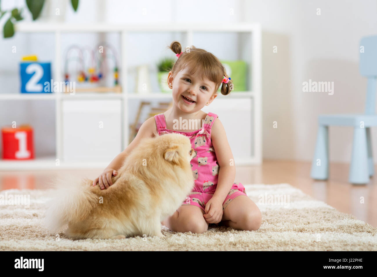 Carina ragazza del bambino seduto sul pavimento con il suo cane Foto Stock