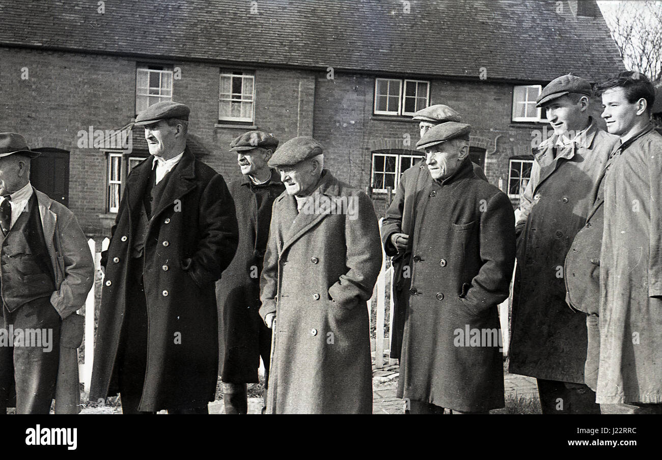 Degli anni Cinquanta, gruppo locale di uomini che indossano cappotti attendere fuori insieme per vedere il foxhunt oltrepassare, Inghilterra, Regno Unito. Foto Stock