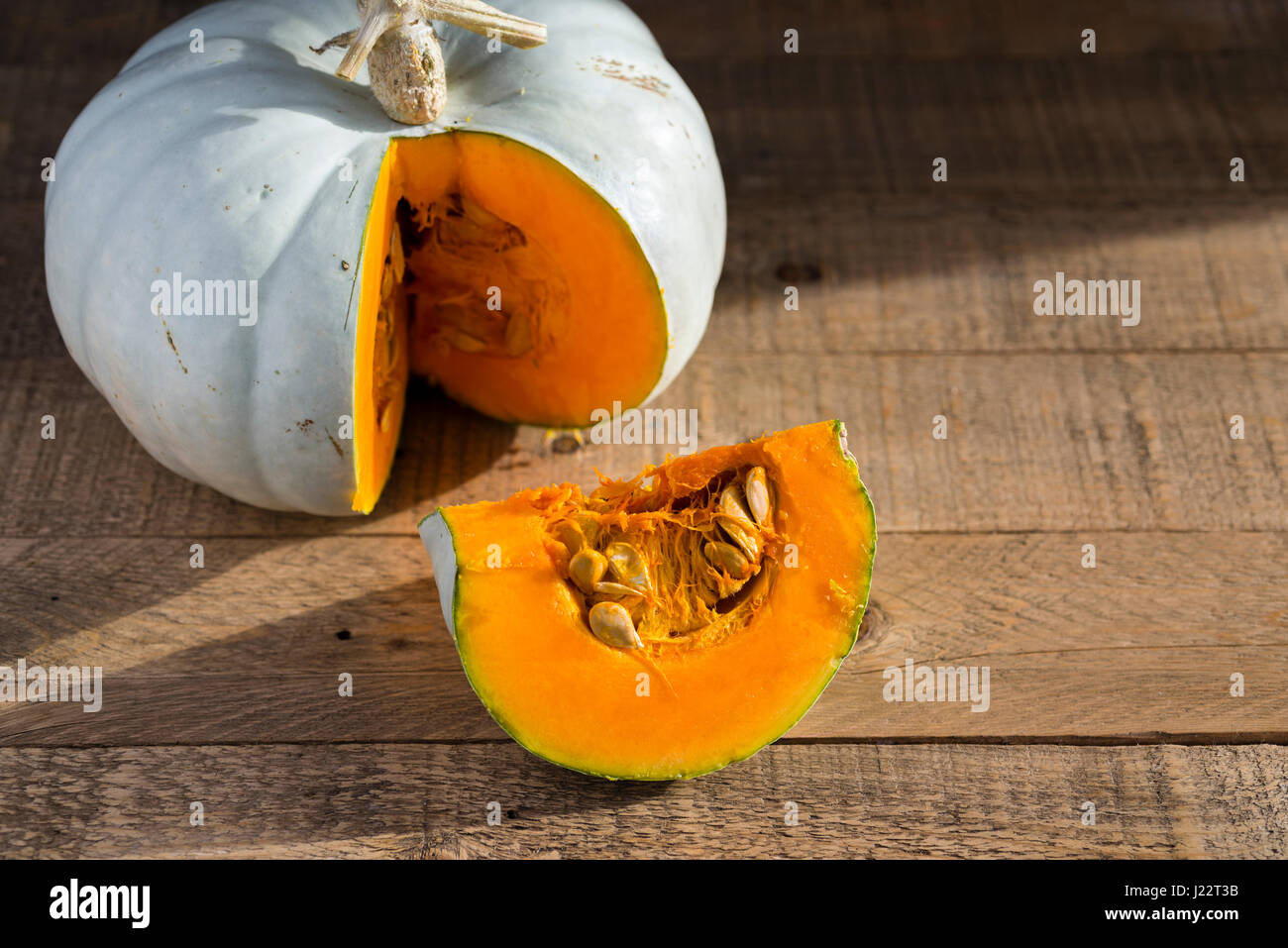 Una Crown Prince Squash essendo tagliato e preparato per la cottura su un tavolo di legno. Foto Stock
