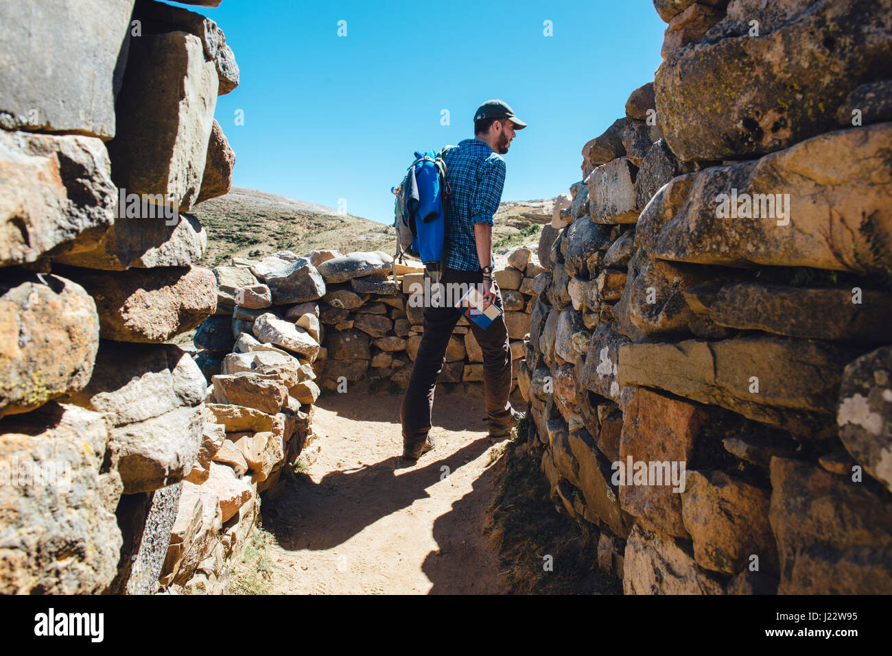 Isla del Sol, lago Titicaca, Bolivia. Uomo con uno zaino e una guida a passeggio tra le rovine di Chinkana Foto Stock