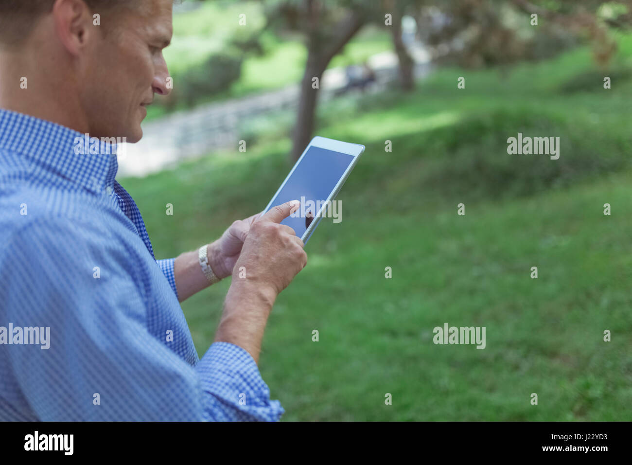 Uomo con mini tablet in un parco Foto Stock