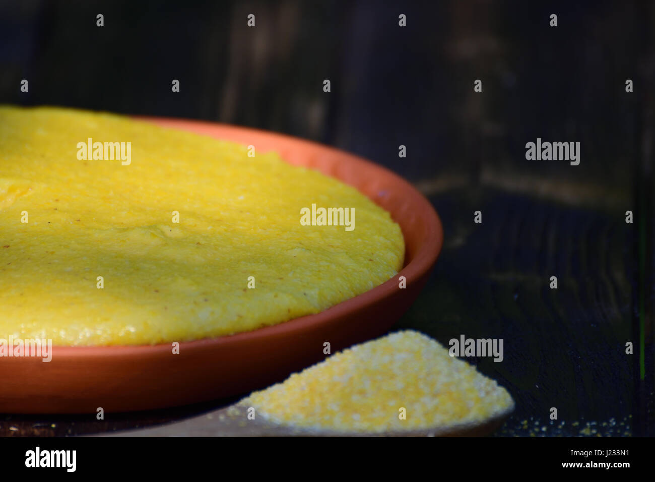 Porridge di mais (polenta o mamaliga) sulla piastra di argilla collocato sul tavolo di legno, all'esterno. Foto Stock