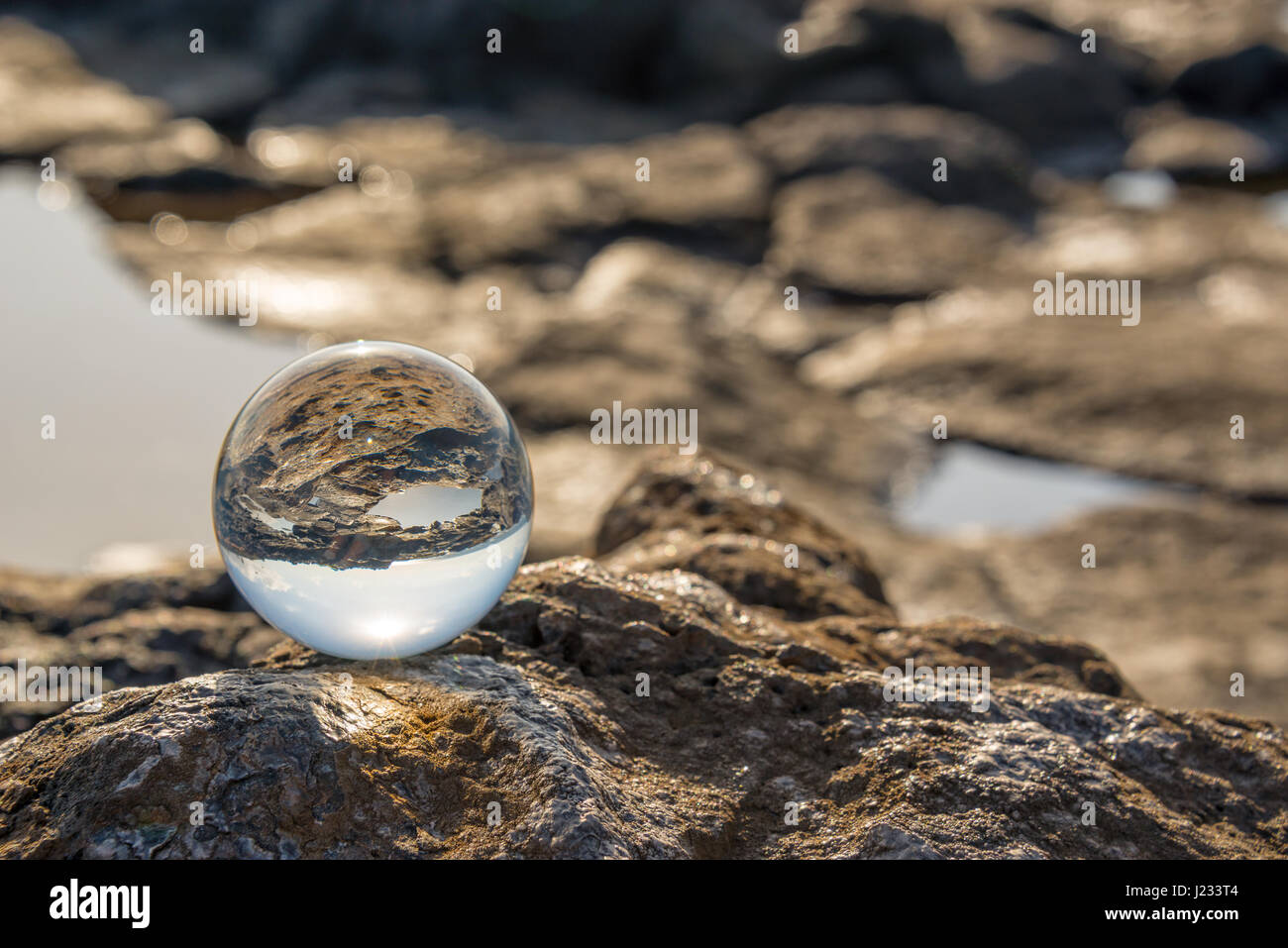 Paesaggio di mare e rocce visto attraverso una sfera di vetro Foto Stock