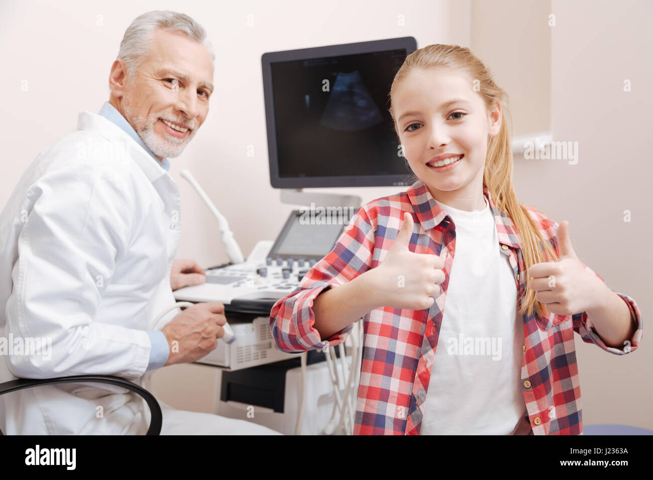 Gioiosa bambina consigliando di scansione a ultrasuoni in clinica Foto Stock