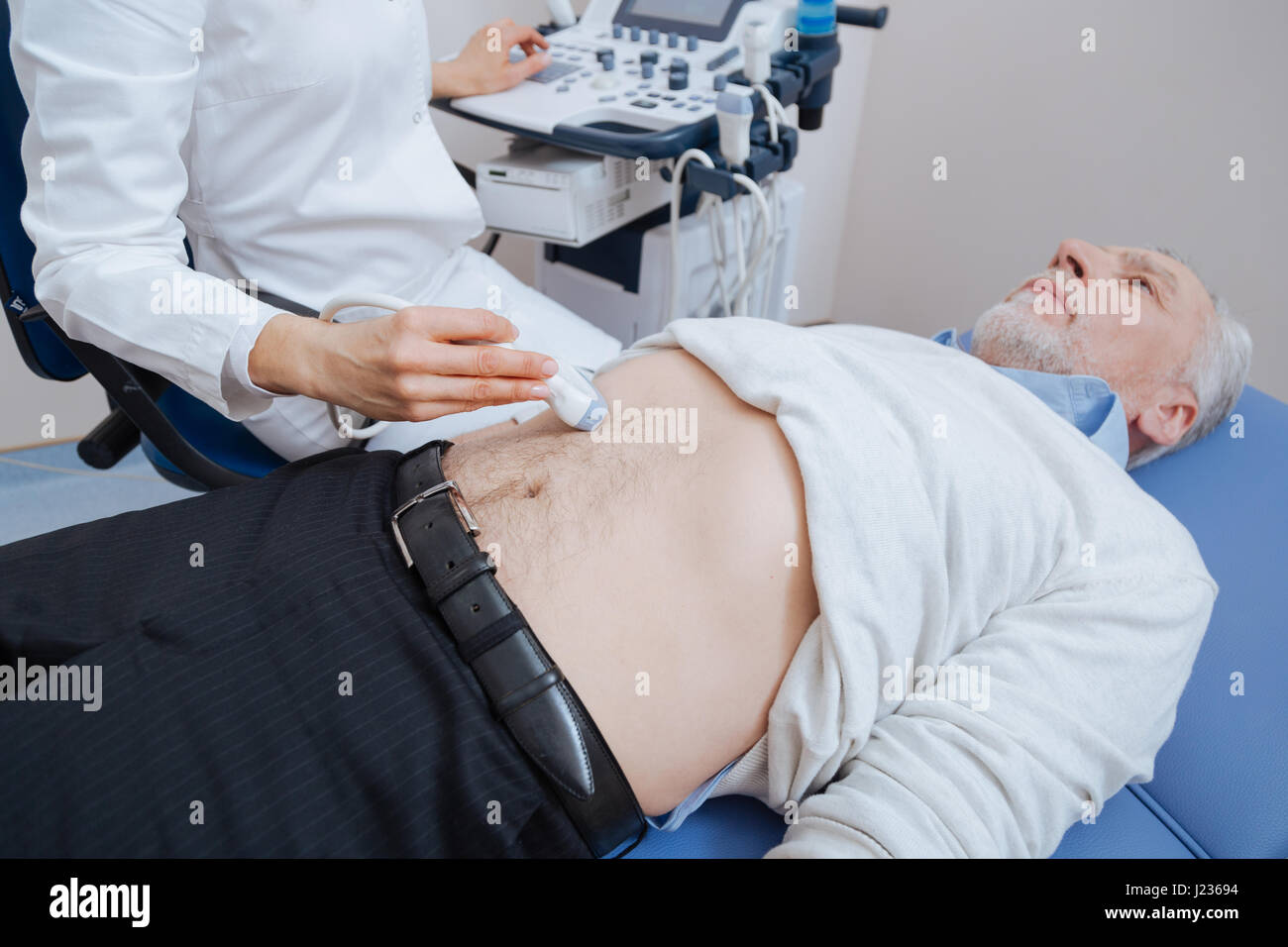 Medico qualificato fornire ultrasuoni monitoraggio addome durante il lavoro Foto Stock