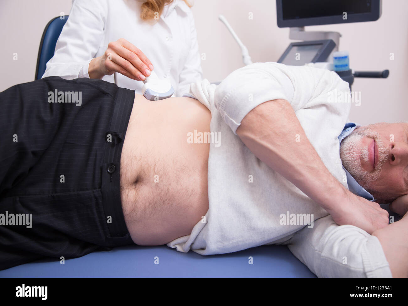 Vecchio paziente avente la scansione a ultrasuoni di addome in clinica Foto Stock