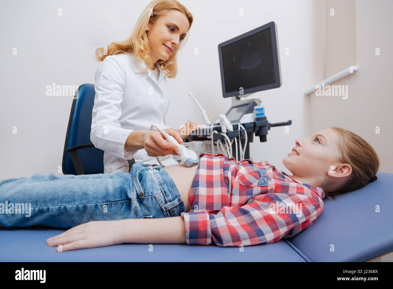 Gentile ecografista fornire ultrasuoni esame addome durante il lavoro Foto Stock