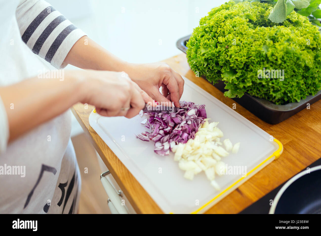 Donna tritare le cipolle sul tavolo da cucina Foto Stock