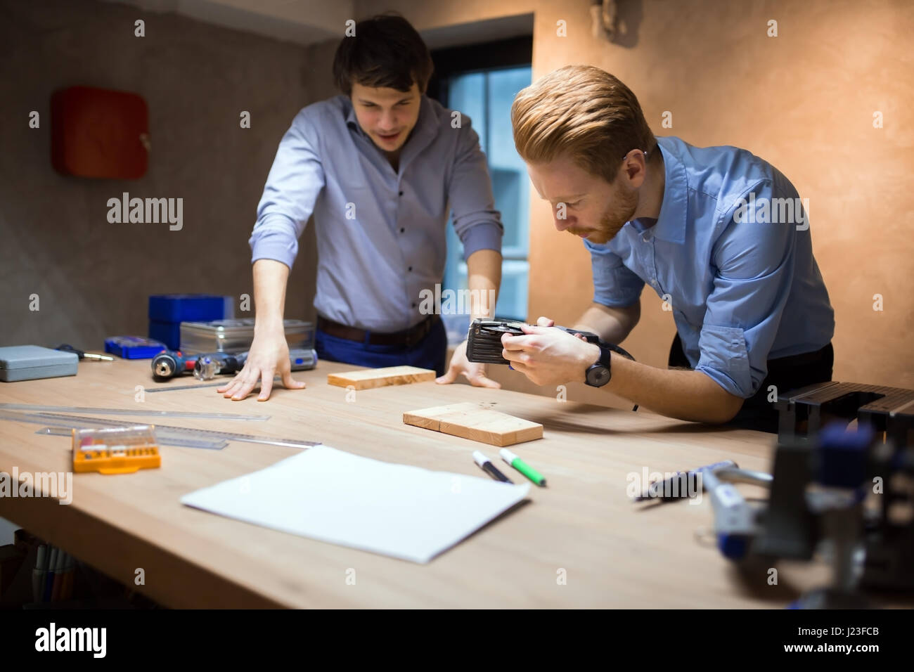 Due designer che lavorano insieme in officina con utensili di precisione Foto Stock