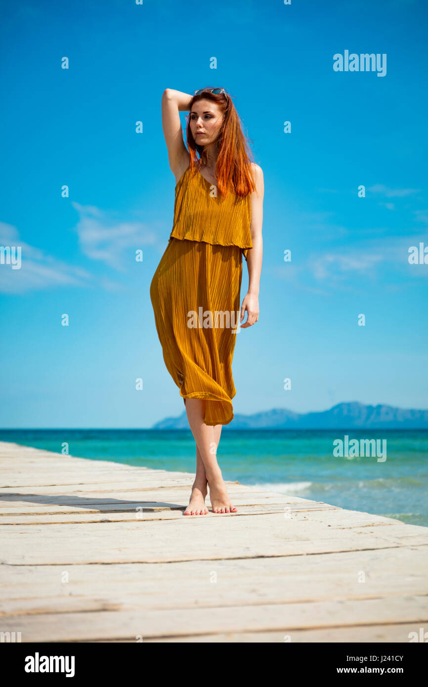 Dai capelli rossi donna al molo di oceano in tempo soleggiato Foto Stock