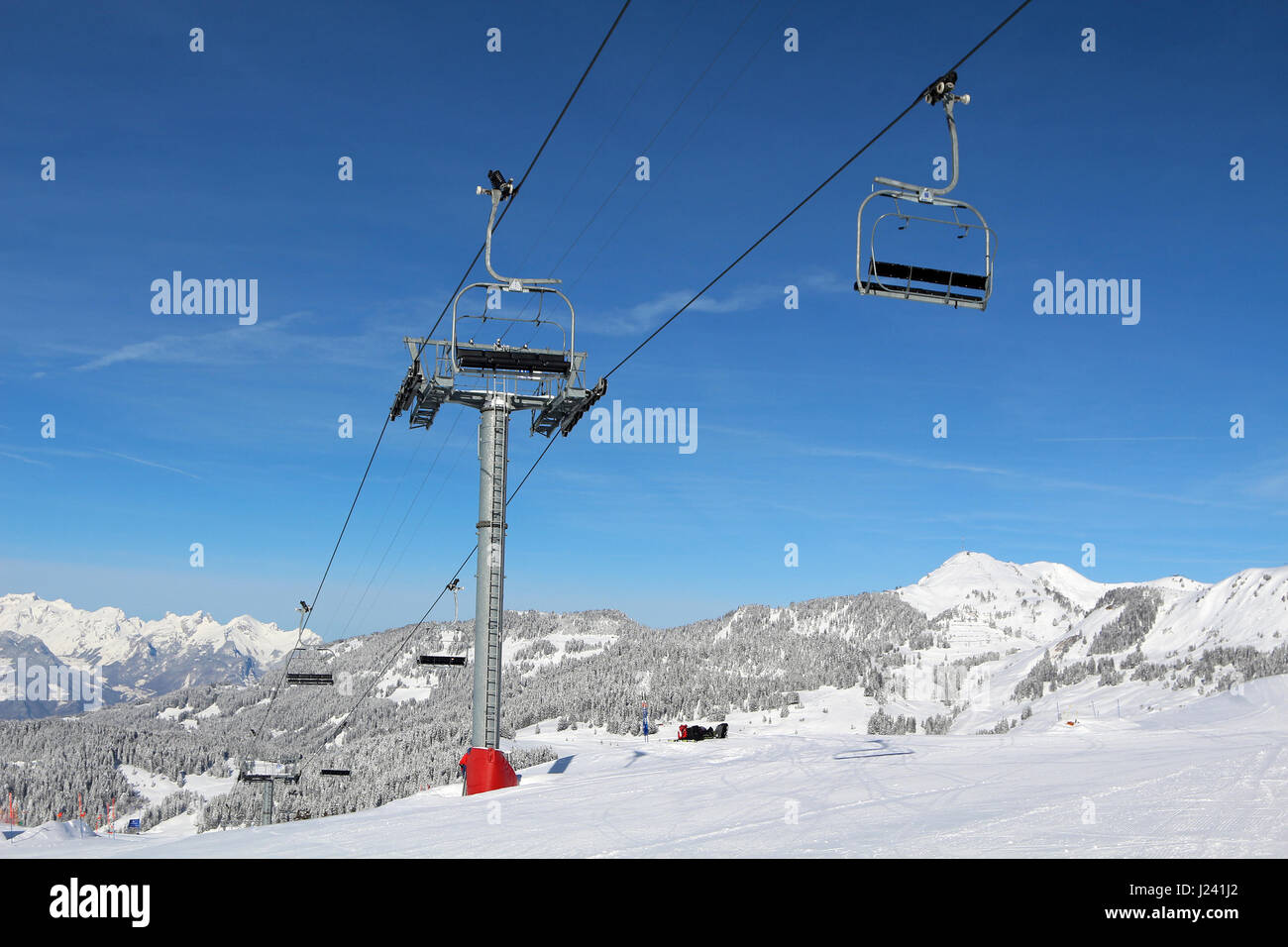 Una seggiovia trasporta gli sciatori e gli snowboarder su un pendio in una stazione sciistica a Villars nelle Alpi Svizzere. Foto Stock