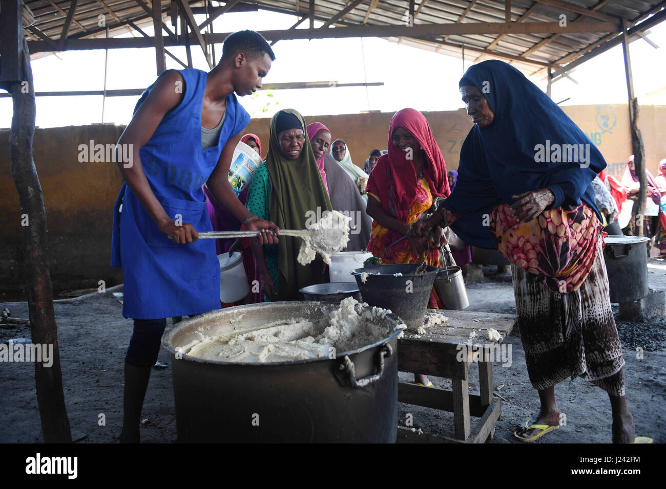 Le donne in Somalia line up per il porridge in corrispondenza di un centro di alimentazione al Badbado Refugee Camp 9 marzo 2017 al di fuori di Mogadiscio, Somalia. La Somalia sta vivendo un periodo di grave siccità e può essere sull orlo della carestia a meno urgente azione umanitaria è presa al più presto. Foto Stock