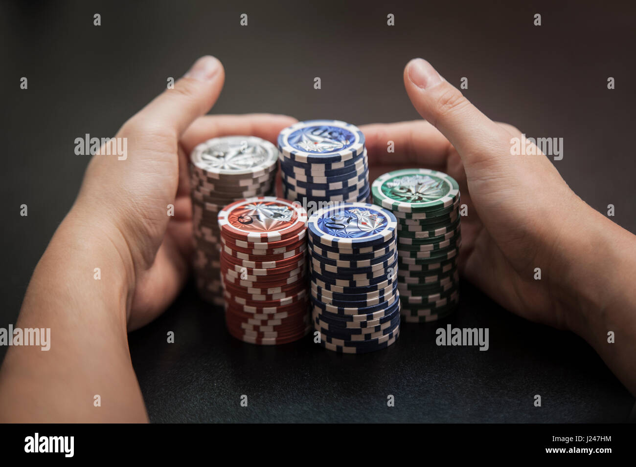 L'uomo le mani tirare a sé un grande mucchio di poker chips Foto Stock