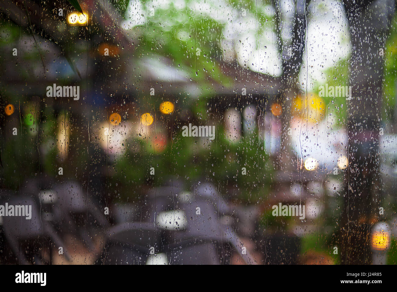 Gocce di pioggia sulla finestra di un ristorante, lo sfondo sfocato di fuori. Foto Stock
