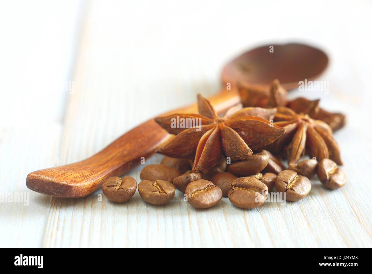 Chicchi di caffè con anice star e in legno vecchio stile a cucchiaio su vintage tavolo in legno degli ingredienti alimentari sfondo. Messa a fuoco selettiva. Bevanda di caffè aroma ingr Foto Stock