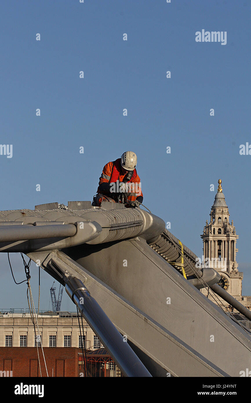 Un ponte ingegnere, indossa una imbracatura di sicurezza, sulla parte superiore del Millennium Bridge, Londra Foto Stock