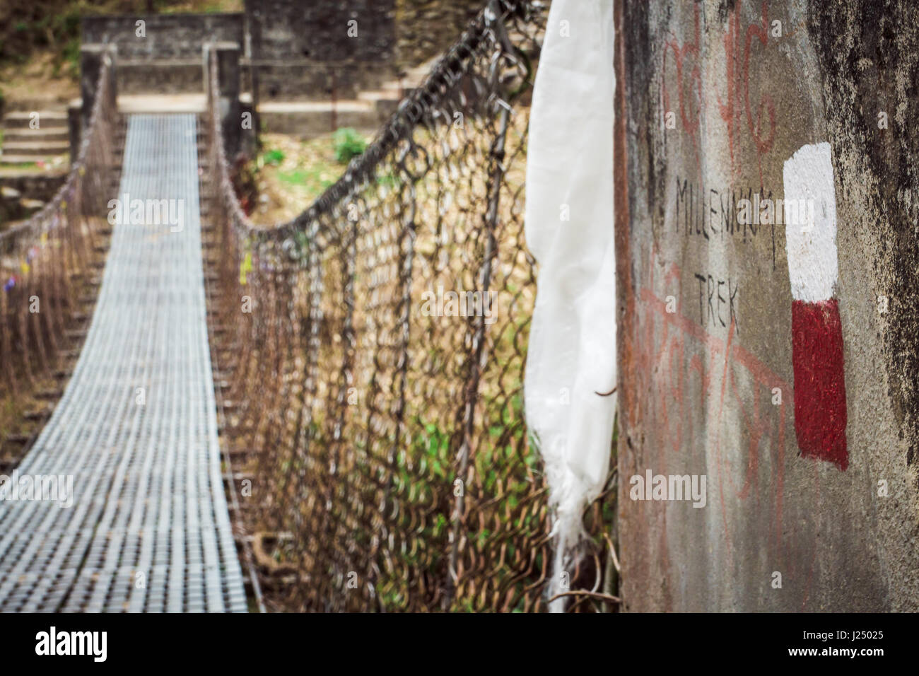 Il Nepal, Marzo 2017: il bianco e il rosso sfolgora sono usati per indicare il circuito di Annapurna trail. Questo ponte si trova vicino al villaggio di Tikhedunga. Annapu Foto Stock