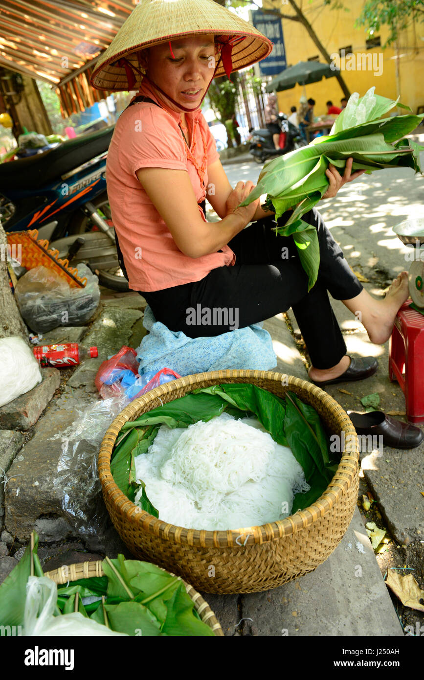Una donna vietnamita tradizionale di vendita riso tagliatelle ( Bún ) nella città vecchia di Hanoi e. Foto Stock