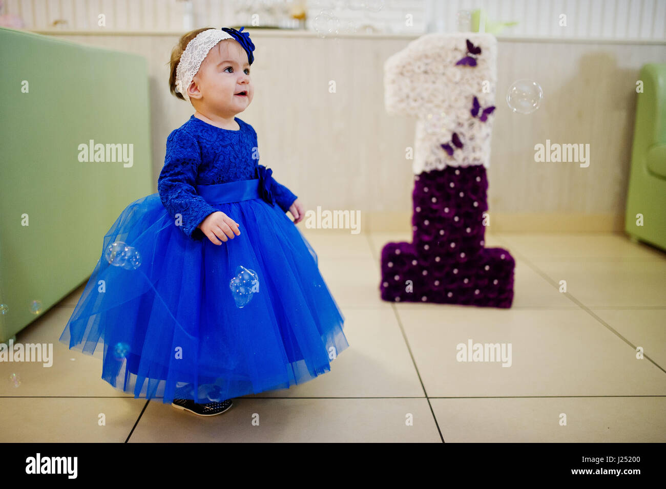 Incantevole piccola bambina al vestito blu gioca con le bolle di sapone. 1  anno giorno di compleanno Foto stock - Alamy