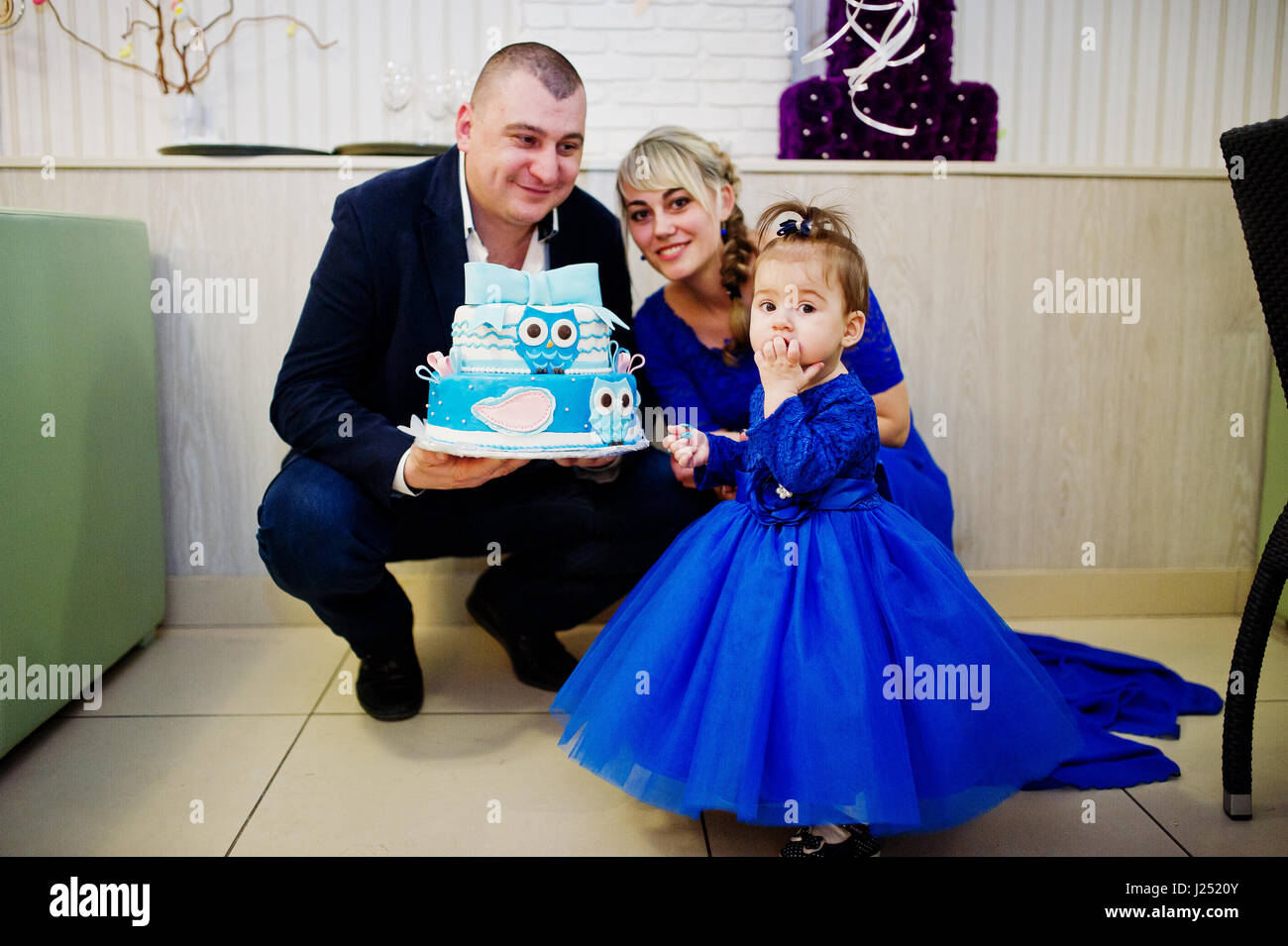 Incantevole piccola bambina al vestito blu con 1 anno di torta di compleanno  e il padre e la madre Foto stock - Alamy