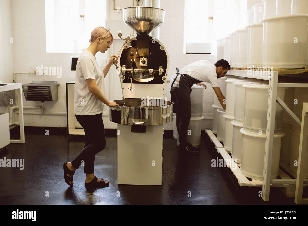 Femmina operativo barista la tostatura del caffè macchina in coffee shop Foto Stock