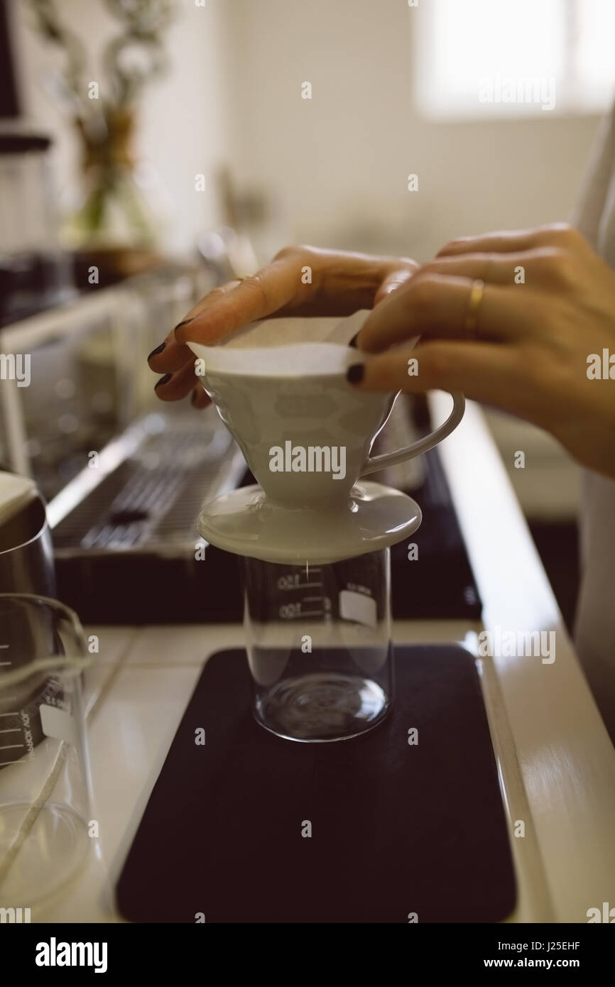 Barista femmina mani imbuto filtrante e la tazza di caffè nella caffetteria Foto Stock