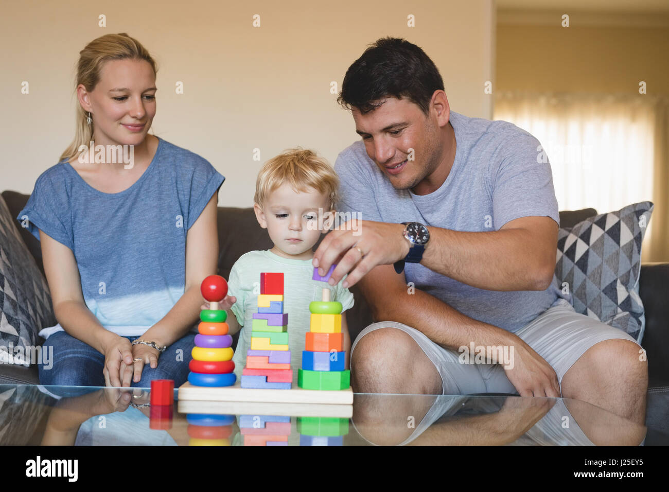 Genitori e figlio giocare con il giocattolo di impilamento nel salotto di casa Foto Stock