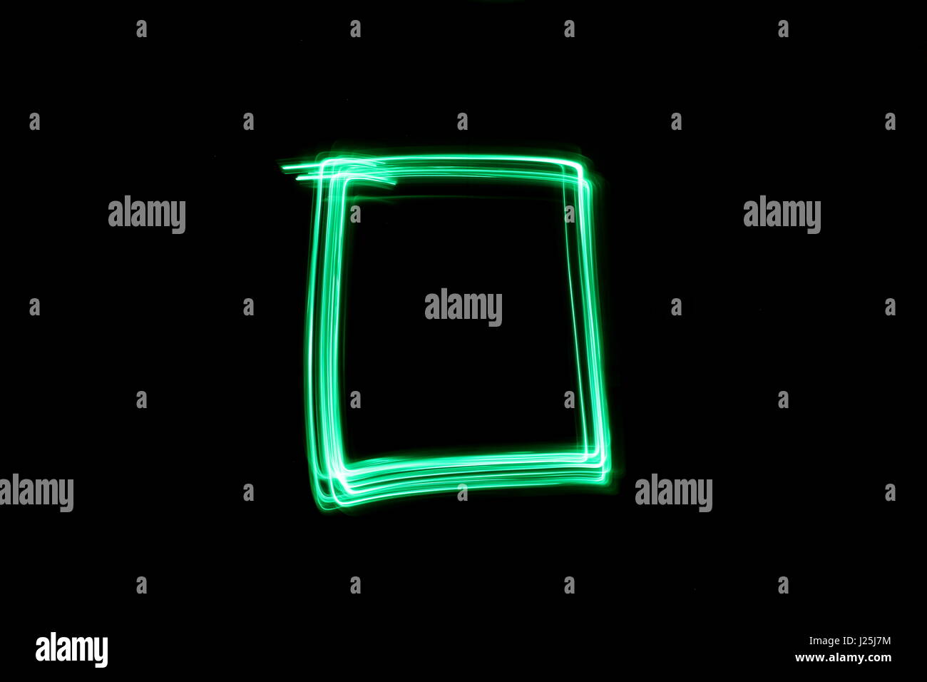 Una lunga esposizione fotografia di neon di colore verde in un astratto casella profilo di forma contro uno sfondo nero. Luce fotografia pittura, di colore in astratto Foto Stock