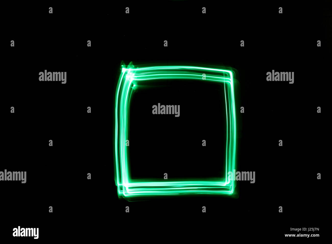 Una lunga esposizione fotografia di neon di colore verde in un astratto casella profilo di forma contro uno sfondo nero. Luce fotografia pittura, di colore in astratto Foto Stock