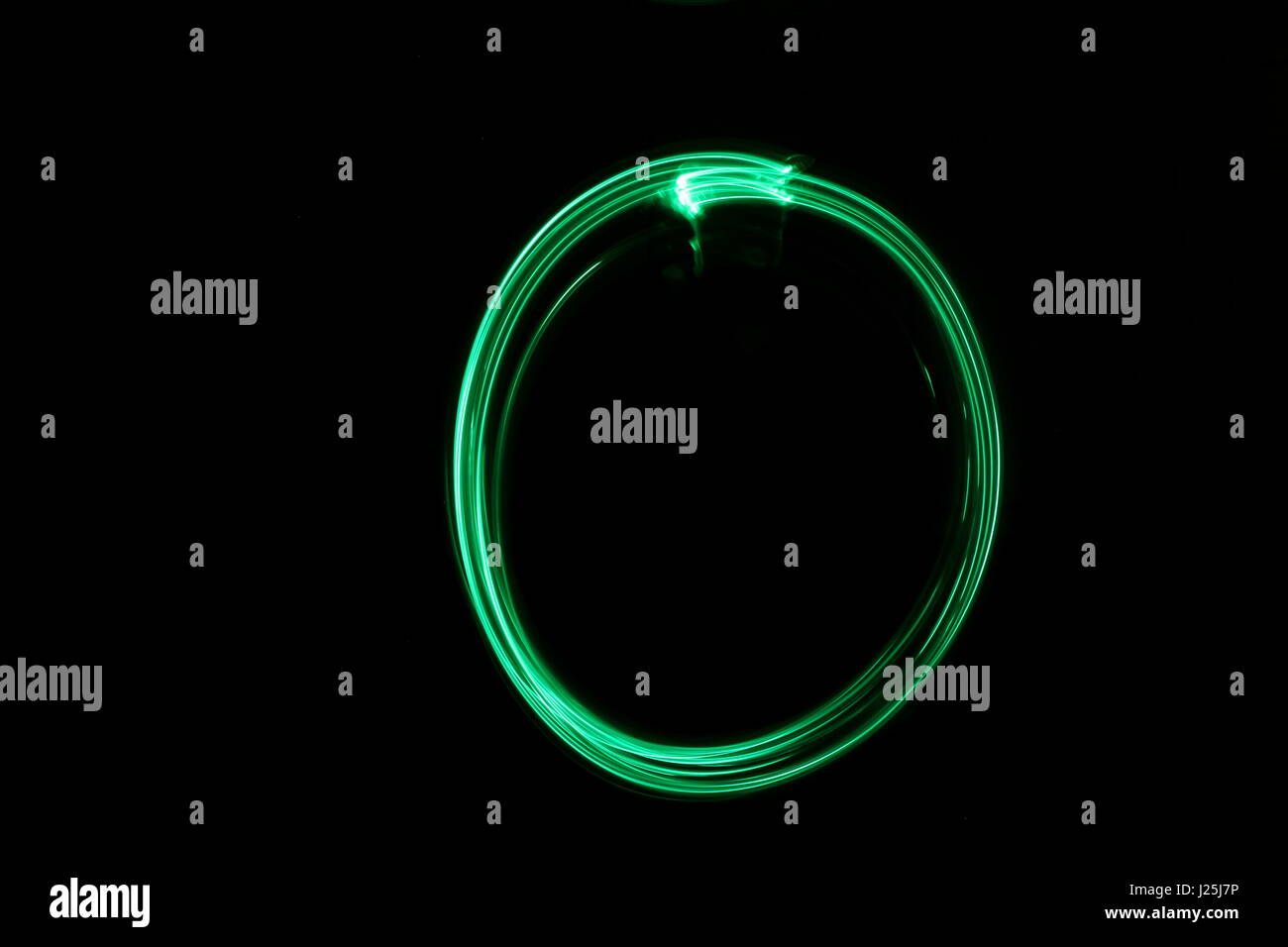 Una lunga esposizione fotografia di neon di colore verde in un cerchio di astratta forma contro uno sfondo nero. Luce fotografia pittura, di colore in astratto Foto Stock