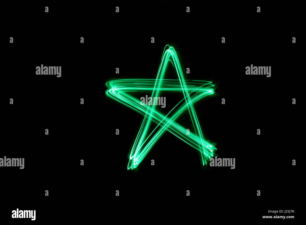 Una lunga esposizione fotografia di neon di colore verde in un astratto star forma del contorno su sfondo nero. Luce fotografia pittura, di colore in astratto Foto Stock