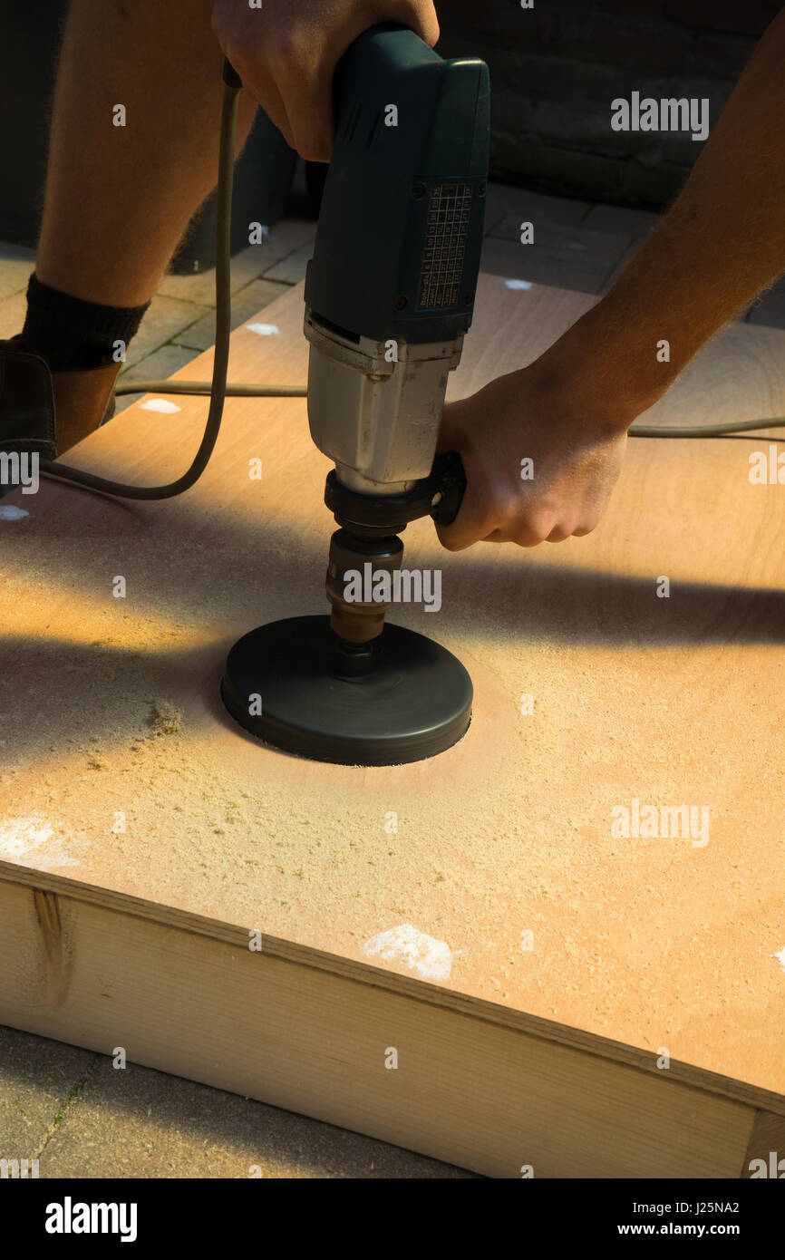 Uomo con la sega a tazza foro di taglio su legno cornhole scheda progetto DIY Foto Stock