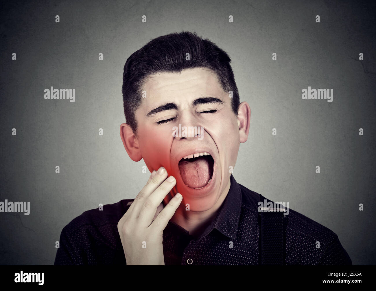 Giovane uomo con mal di denti sensibili al problema della corona di piangere urlando dal dolore di toccare al di fuori della bocca con la mano isolato su sfondo grigio. Ronzio negativa Foto Stock