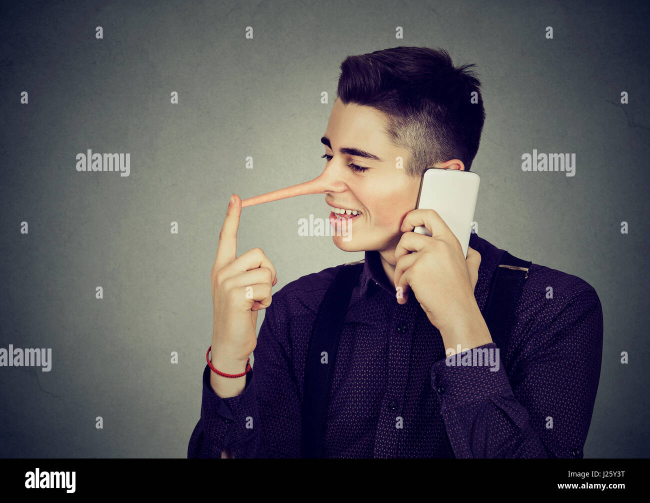 Felice giovane con il naso lungo parlando al telefono cellulare isolata sul muro grigio Sfondo. Concetto bugiardo. Emozione umana sentimenti, tratti caratteriali Foto Stock