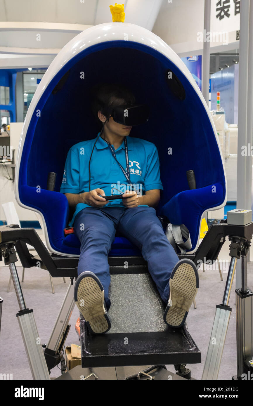 Ragazzo asiatico riproduzione VR gioco su VR uovo sedia Foto Stock