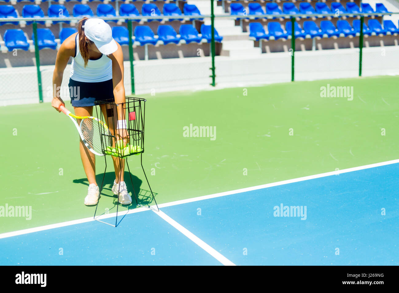 Femmina giocatore di tennis la pratica di servizio con la sfera cestello essendo a portata di mano Foto Stock