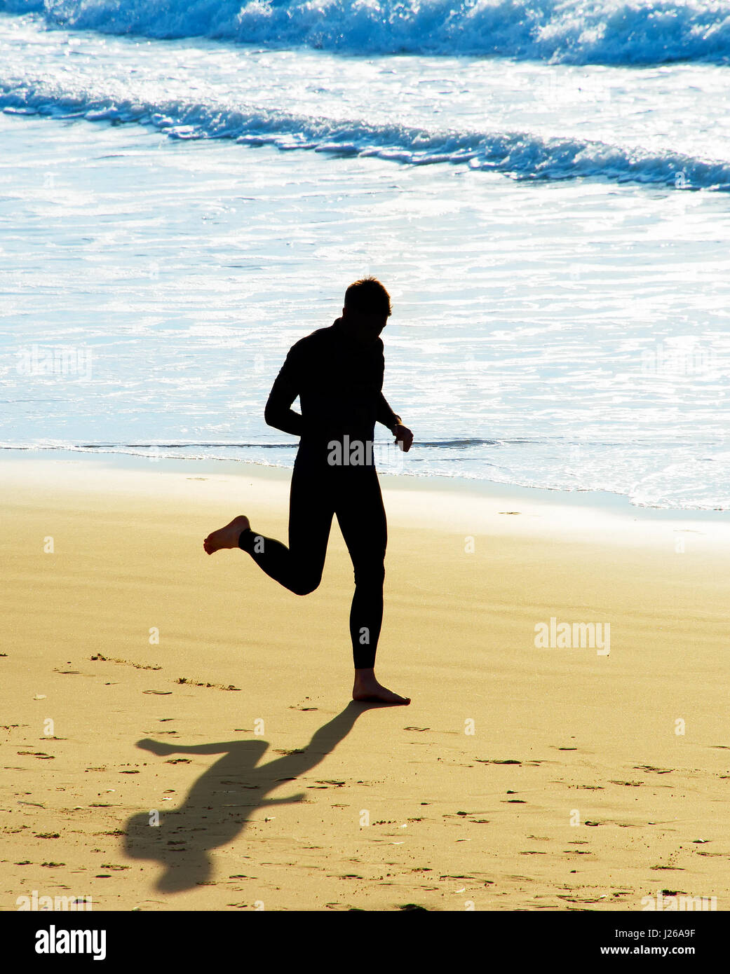 Uomo bello correre sulla spiaggia, silhouette Foto Stock
