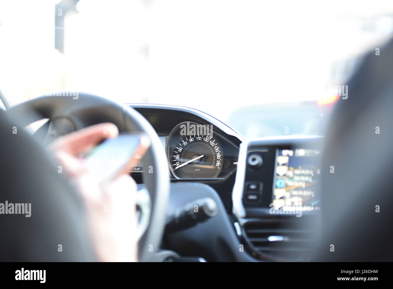 Trattenendo il volante e guidare una vettura utilizzando costruito nel sistema di navigazione durante il tramonto con i riflessi del sole Foto Stock