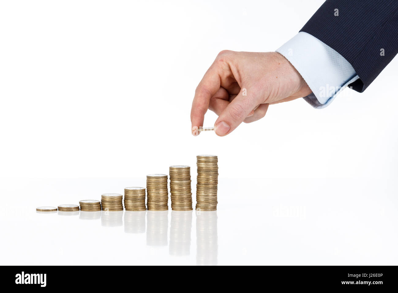 Close up di imprenditore a mano uno di impilamento delle monete in euro in aumento le colonne su sfondo bianco Foto Stock