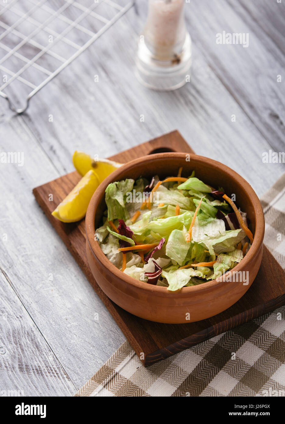 Fresca insalata mista servita in un piatto di argilla su un tavolo di legno. Foto Stock