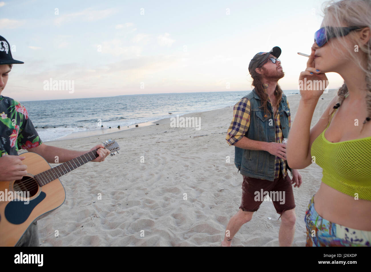 Gli amici di riproduzione di musica insieme su una spiaggia Foto Stock