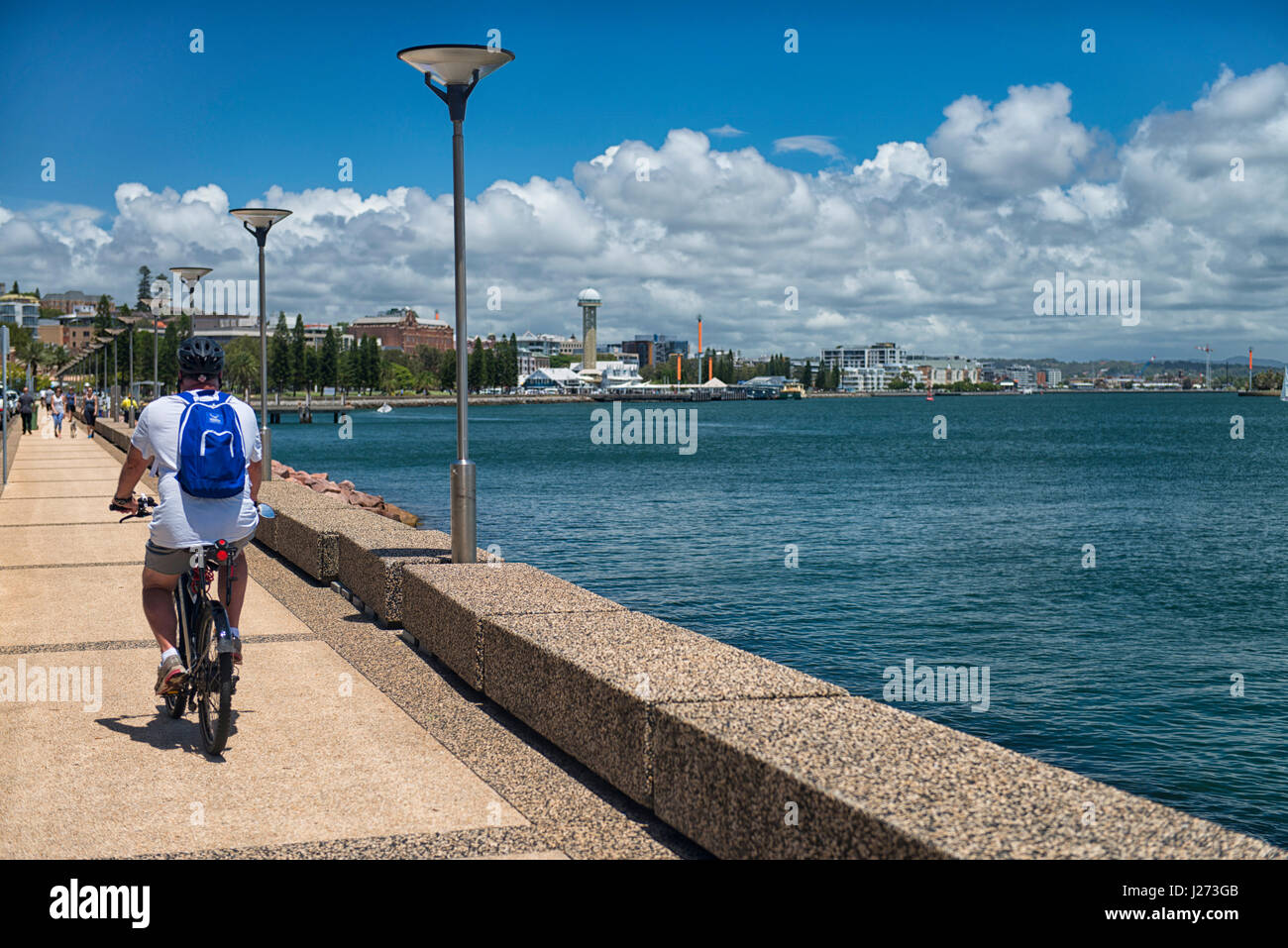 Un ciclista biciclette lungo il fiume Hunter lungo Wharf Road verso il molo, Newcastle, Nuovo Galles del Sud, Australia. Foto Stock