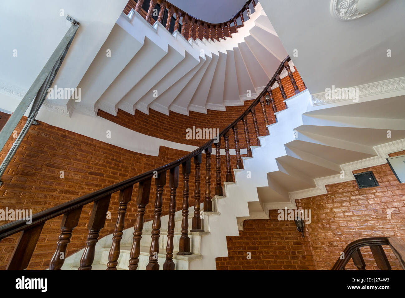 Un bianco scalinata a spirale è in avvolgimento in una casa di mattoni Foto Stock