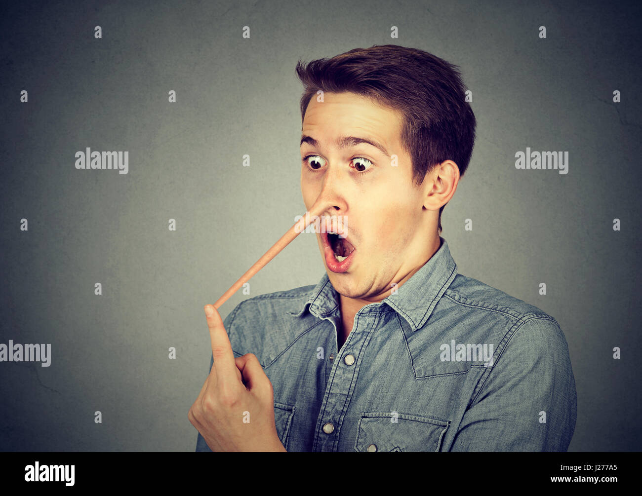 Uomo con il naso lungo isolato sul muro grigio Sfondo. Concetto bugiardo. Volto umano espressioni, emozioni, sentimenti. Foto Stock