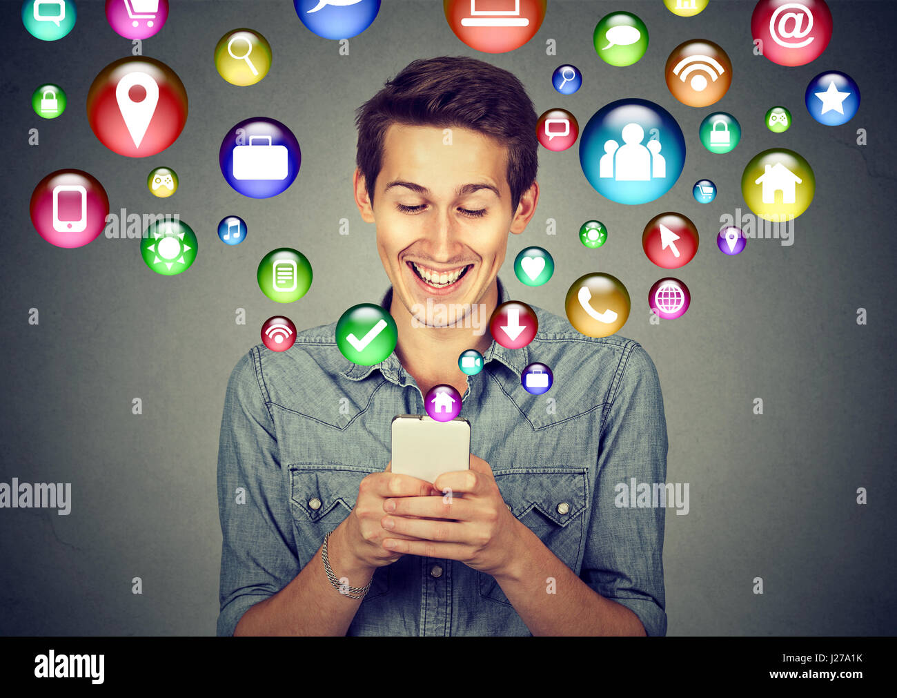 La tecnologia di comunicazione mobile phone high tech concetto. Felice l'uomo utilizzando messaggi di testo sullo smartphone social media le icone delle applicazioni battenti fuori del cellulare Foto Stock