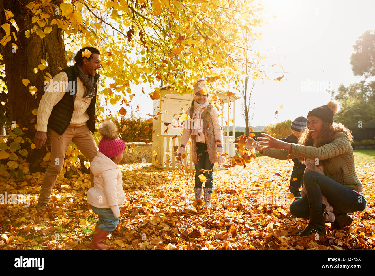 La famiglia gioca con foglie di autunno in giardino insieme Foto Stock
